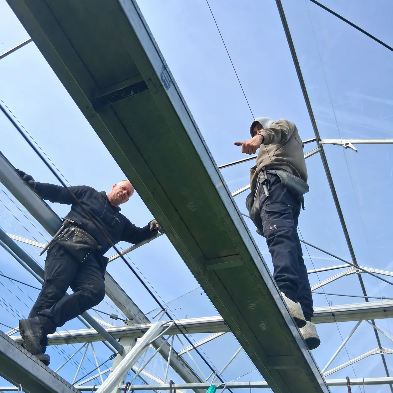 Twee vakmensen aan het werk op de draagconstructie van een kasdek